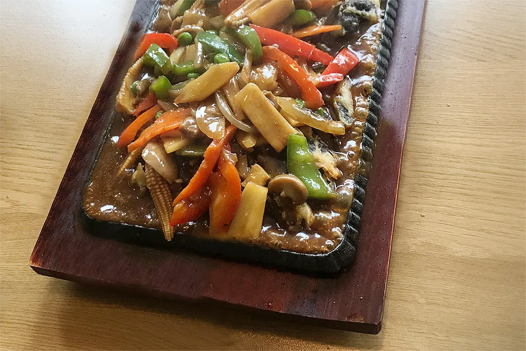 Sizzling anka med grönsaker på gjutjärnsplatta
